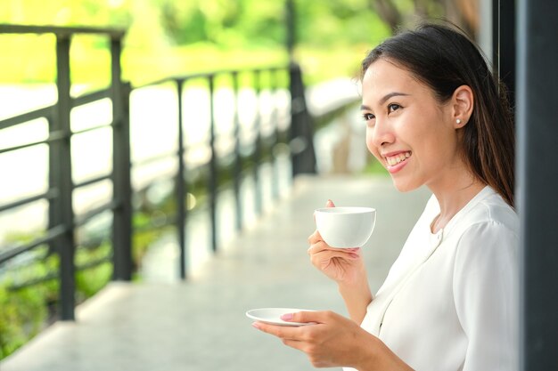 Giovane donna che beve caffè caldo nel caffè del marciapiede