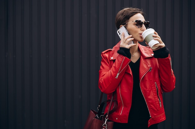 Giovane donna che beve caffè e beve camminando per strada