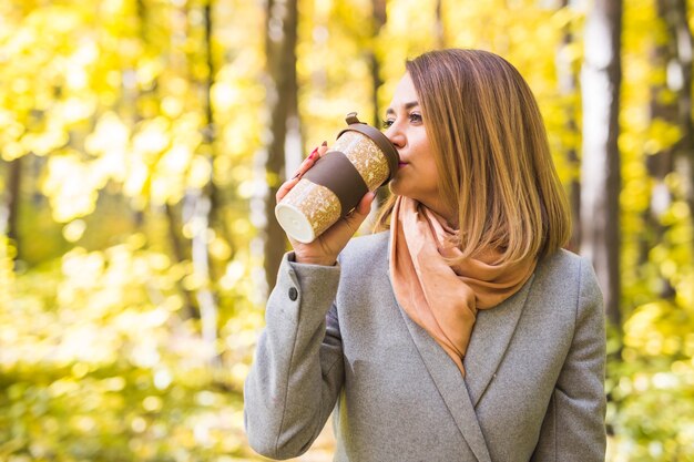 giovane donna che beve caffè nel parco in autunno