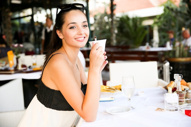 Giovane donna che beve il caffè nel ristorante