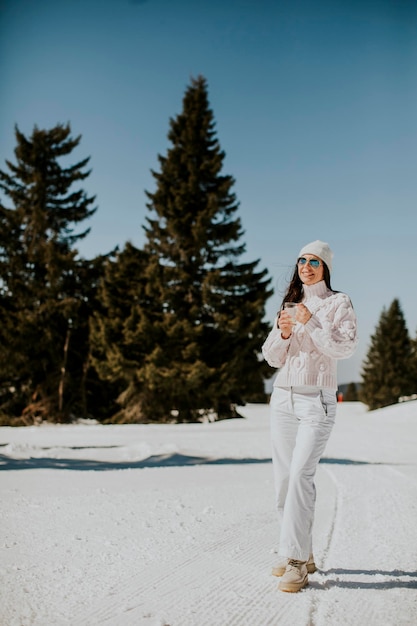 Giovane donna che beve limonata sulla pista da sci di montagna