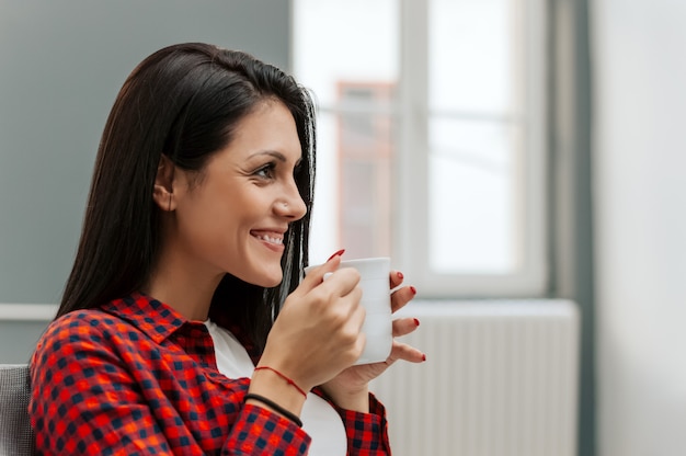 Giovane donna che beve tazza di caffè in tempo di pausa.