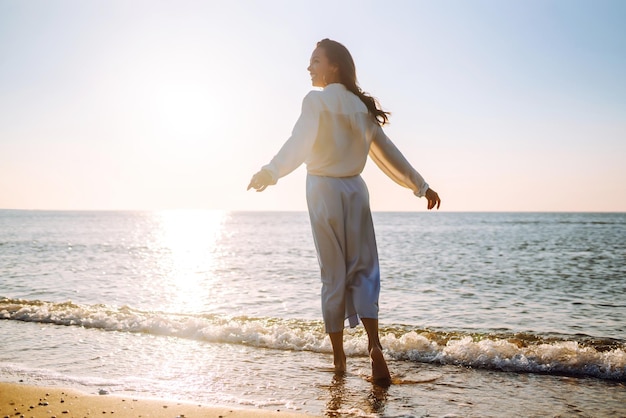 Giovane donna che cammina al tramonto sulla spiaggia Ora legale Concetto di stile di vita del fine settimana di viaggio