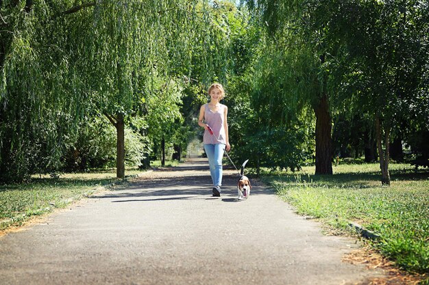 Giovane donna che cammina cane sulla passerella nel parco