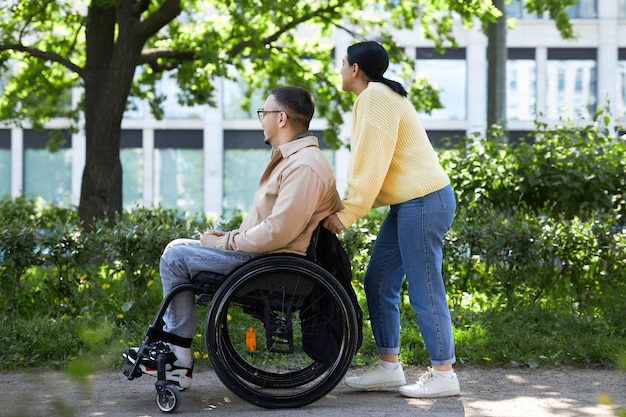 Giovane donna che cammina con la sua amica con disabilità in città in un giorno d'estate