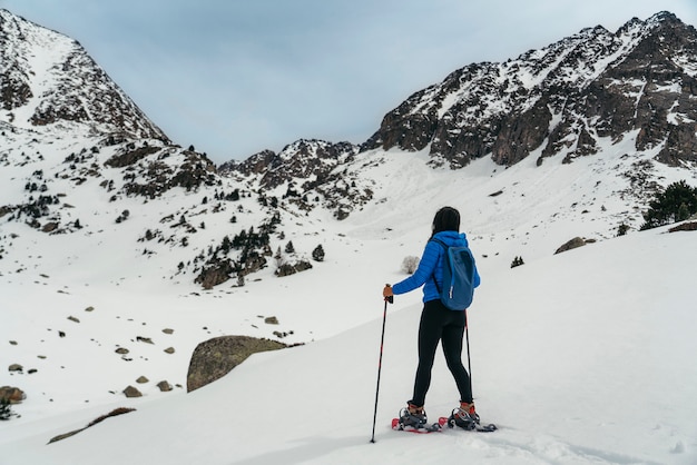 Giovane donna che cammina con le racchette da neve in alta montagna