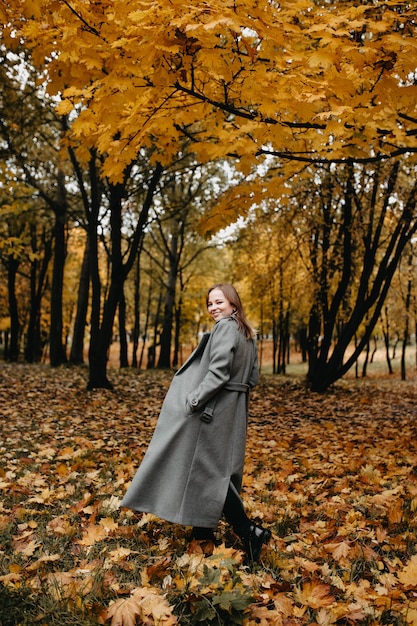 giovane donna che cammina nel parco autunnale con un lungo cappotto