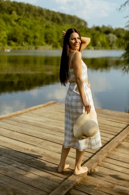 Giovane donna che cammina sul molo di legno al lago calmo