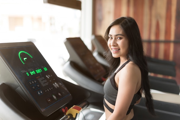 Giovane donna che cammina sul tapis roulant e in palestra