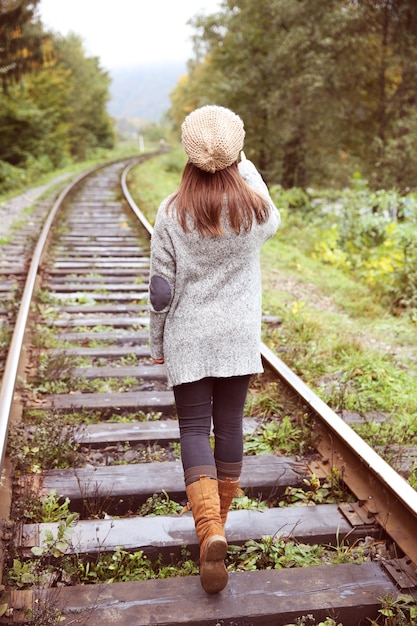 Giovane donna che cammina sulla rotaia dei binari ferroviari