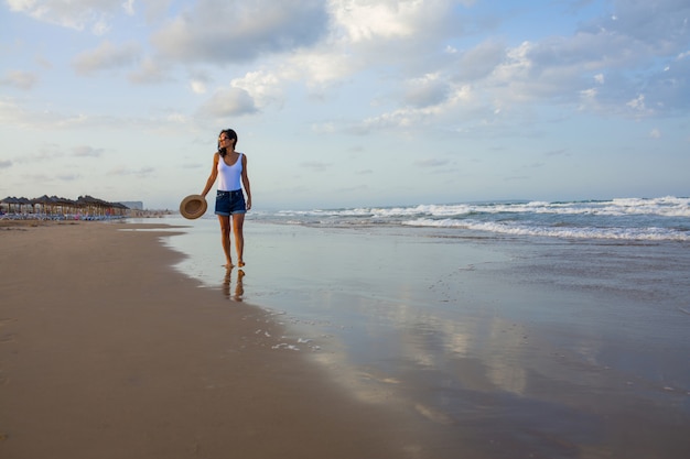 Giovane donna che cammina sulla spiaggia