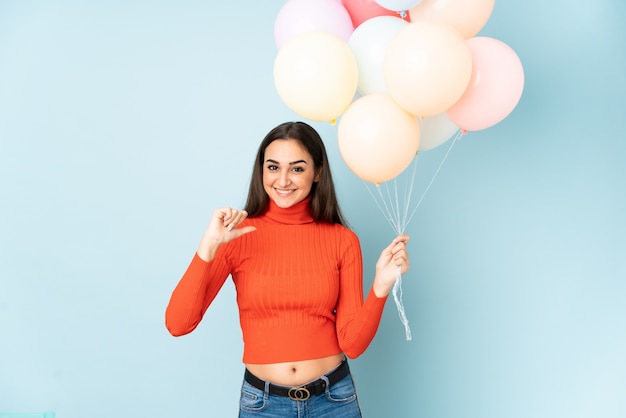 Giovane donna che cattura molti palloncini