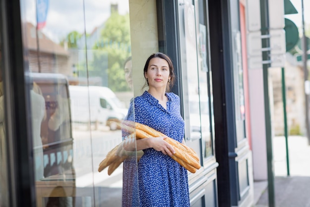 Giovane donna che compra una baguette francese