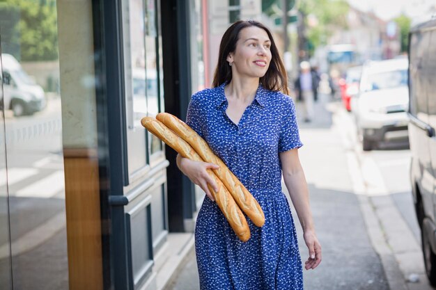 Giovane donna che compra una baguette francese