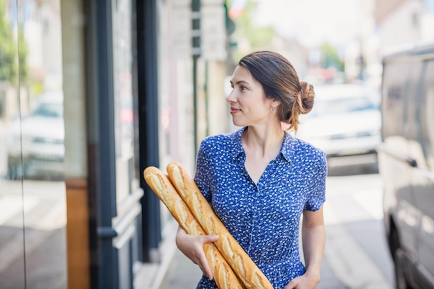 Giovane donna che compra una baguette francese