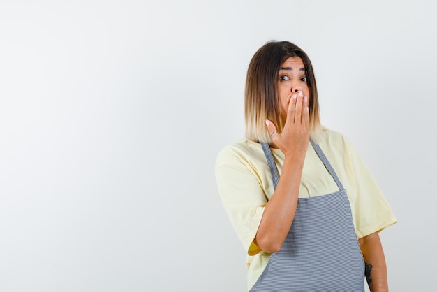 Giovane donna che copre la bocca con le mani su sfondo bianco