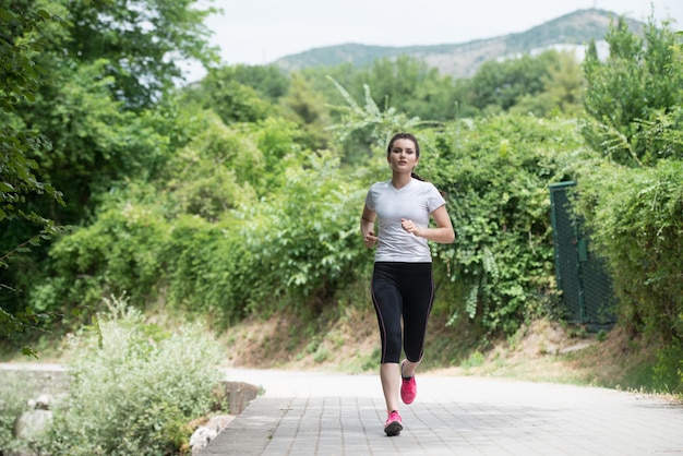 Giovane donna che corre nella foresta boscosa zona formazione ed esercizio per Trail Run Marathon Endurance Fitness stile di vita sano concetto