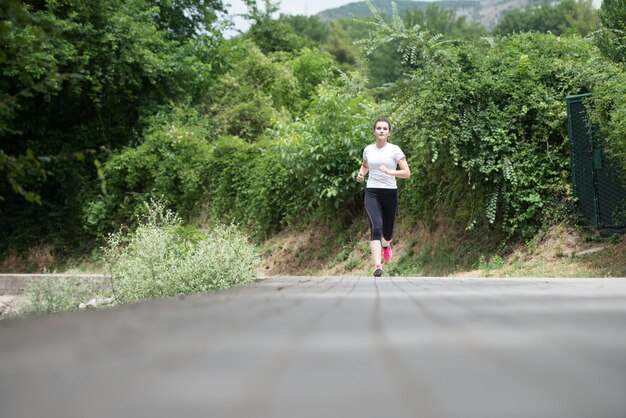 Giovane donna che corre nella foresta boscosa zona formazione ed esercizio per Trail Run Marathon Endurance Fitness stile di vita sano concetto