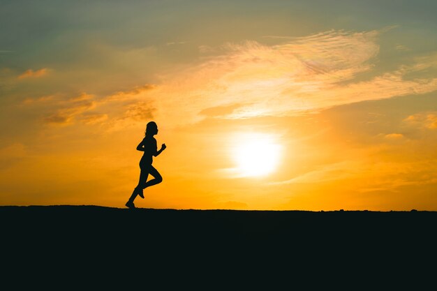 Giovane donna che corre su una strada rurale durante il tramonto