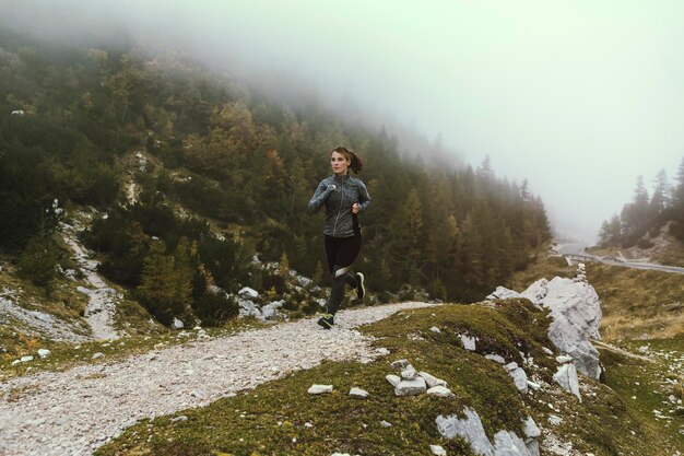 Giovane donna che corre sul campo durante il tempo nebbioso