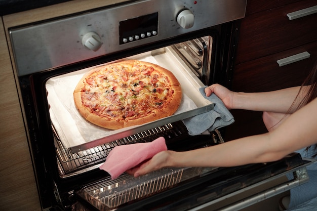 Giovane donna che cucina la pizza