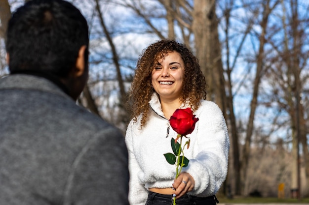 Giovane donna che dà una rosa rossa al suo fidanzato