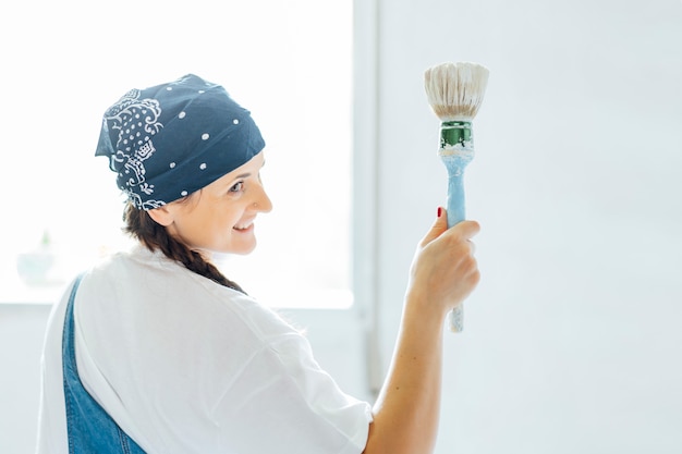 Giovane donna che dipinge le pareti della sua casa.