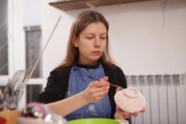 Giovane donna che dipinge una ciotola di argilla al corso di ceramica