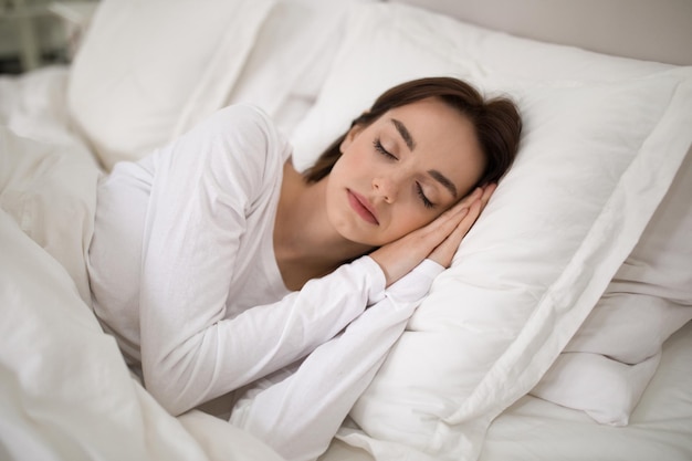 Giovane donna che dorme con le mani sotto la testa