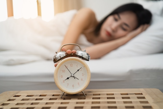 Giovane donna che dorme e sveglia in camera da letto a casa