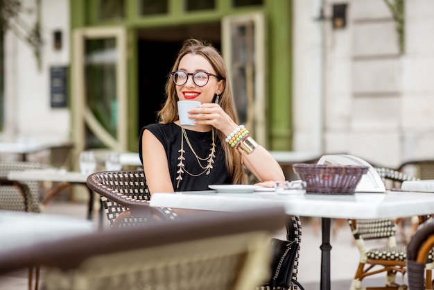 Giovane donna che fa colazione con caffè e croissant seduti all'aperto sulla tipica terrazza del caffè francese durante la mattinata in Francia