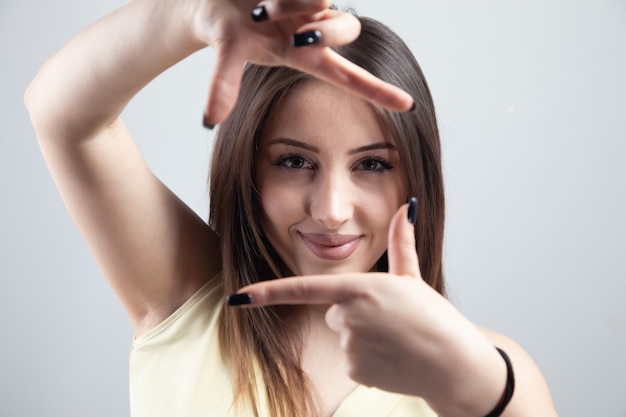 Giovane donna che fa cornice con le mani.