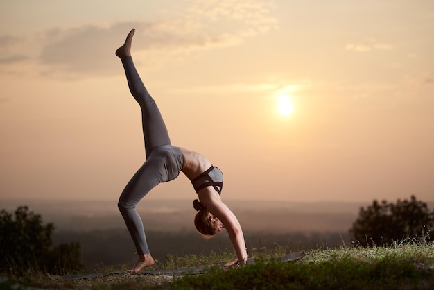 Giovane donna che fa esercizi di yoga all'aperto al tramonto