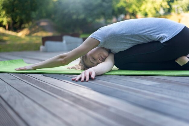 Giovane donna che fa esercizi di yoga di allungamento del corpo nel parco verde Praticando yoga all'aperto in natura