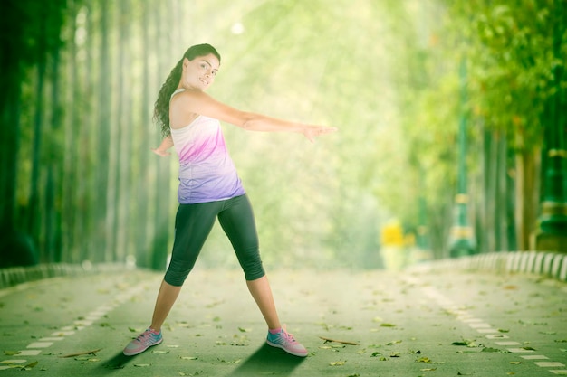 Giovane donna che fa esercizio di stretching al parco