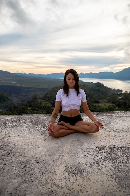 Giovane donna che fa esercizio di yoga fitness all'aperto in un bellissimo paesaggio di montagne. Alba del mattino. Tempo di meditazione