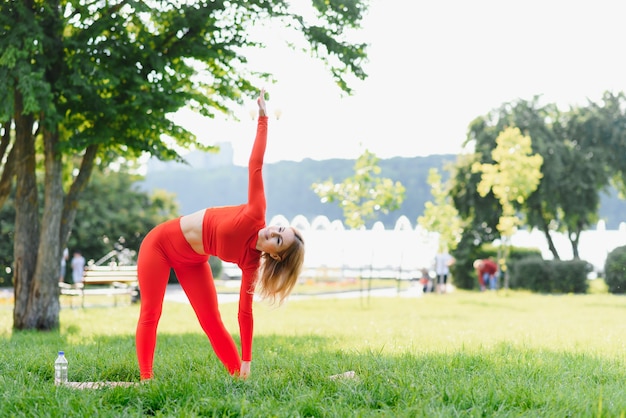 Giovane donna che fa esercizio di yoga nel parco verde