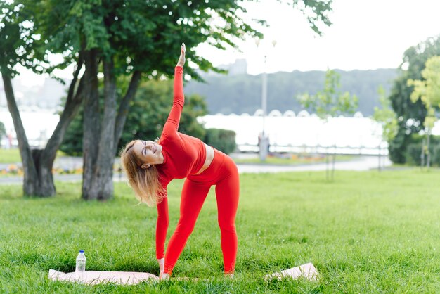 Giovane donna che fa esercizio di yoga nel parco verde