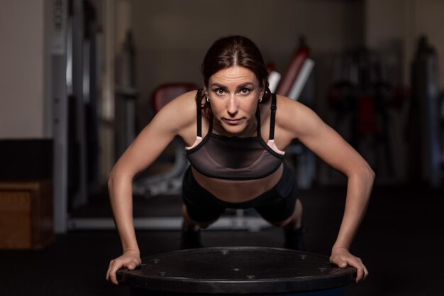 Giovane donna che fa flessioni in palestra