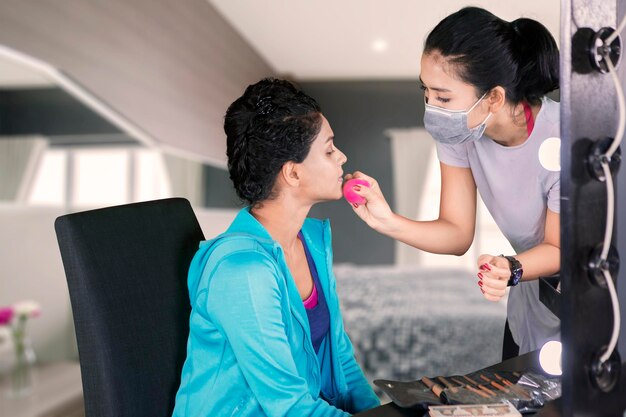 Giovane donna che fa il make-up per il suo cliente