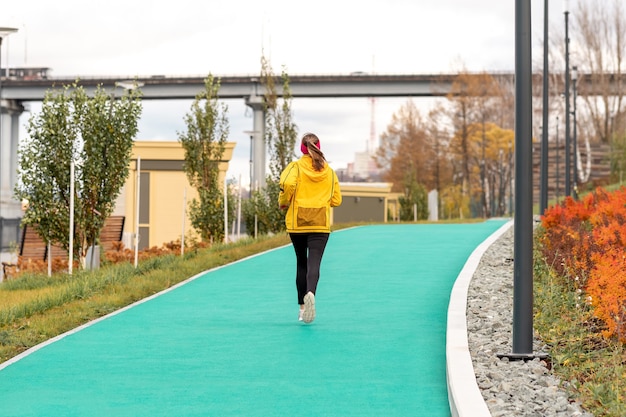 Giovane donna che fa jogging nel parco autunnale vicino al fiume