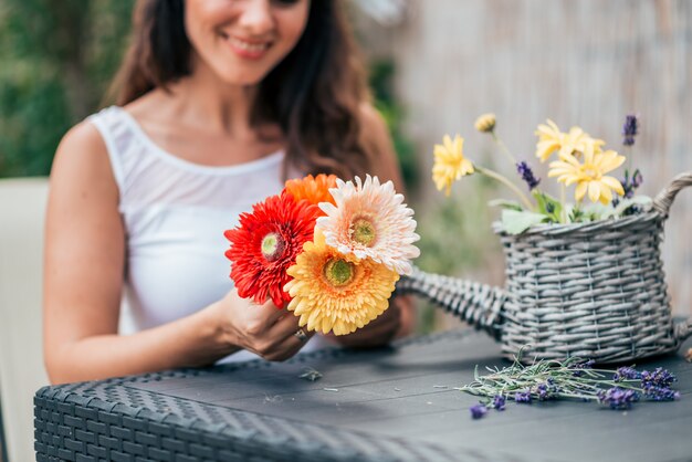 Giovane donna che fa la disposizione dei fiori in un cestino.