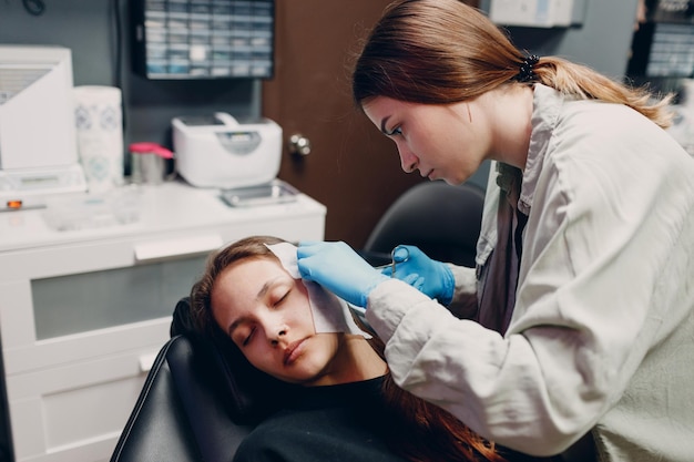 Giovane donna che fa piercing all'orecchio al salone di bellezza