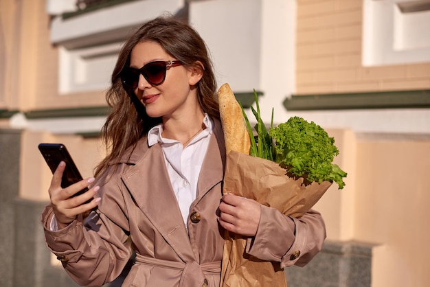 Giovane donna che fa shopping e chiama un taxi tramite app mobile ragazza attraente usa il telefono cellulare per strada