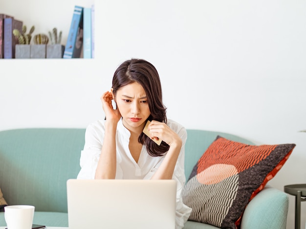 Giovane donna che fa shopping online con carta di credito e laptop a casa