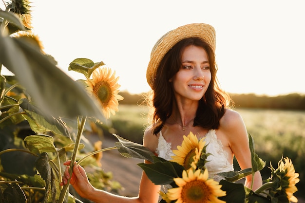 Giovane donna che fa una passeggiata nel campo di girasoli al mattino