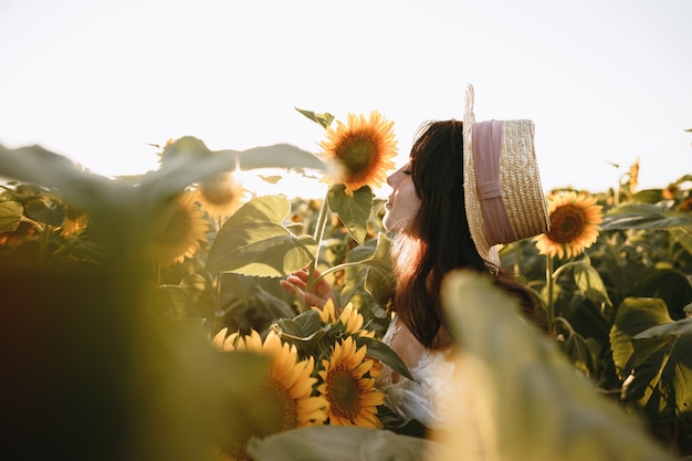 Giovane donna che fa una passeggiata nel campo di girasoli al mattino