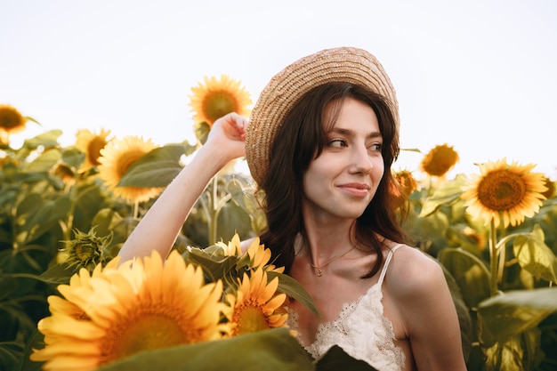 Giovane donna che fa una passeggiata nel campo di girasoli al mattino