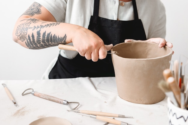 Giovane donna che fa vaso di terracotta nel laboratorio di ceramica