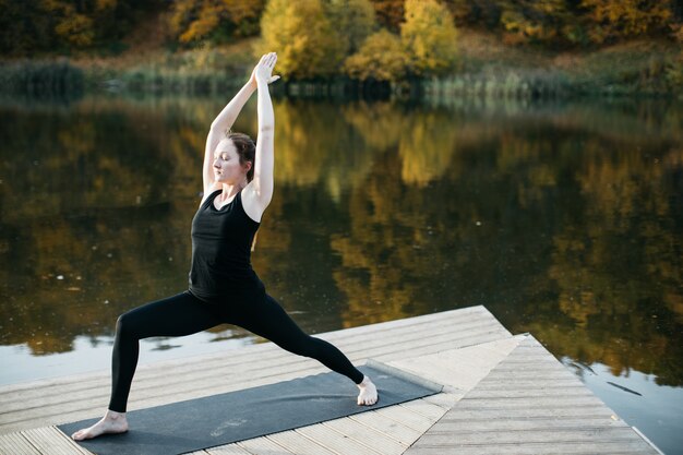 Giovane donna che fa yoga asana in natura vicino al lago